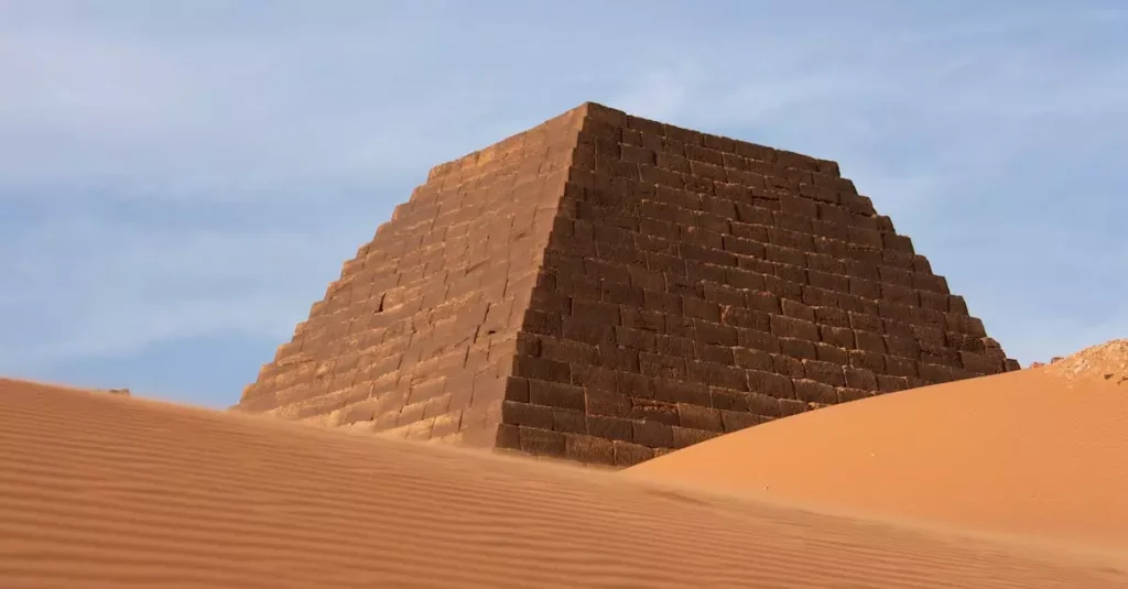 A striking image of an ancient pyramid amidst desert dunes under clear blue skies.