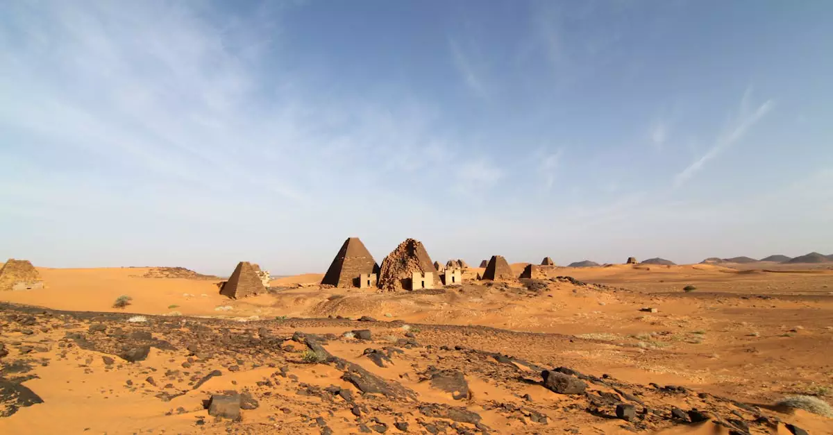 Ancient Meroe pyramids stand in the arid desert under a clear sky, showcasing Sudan's rich history.