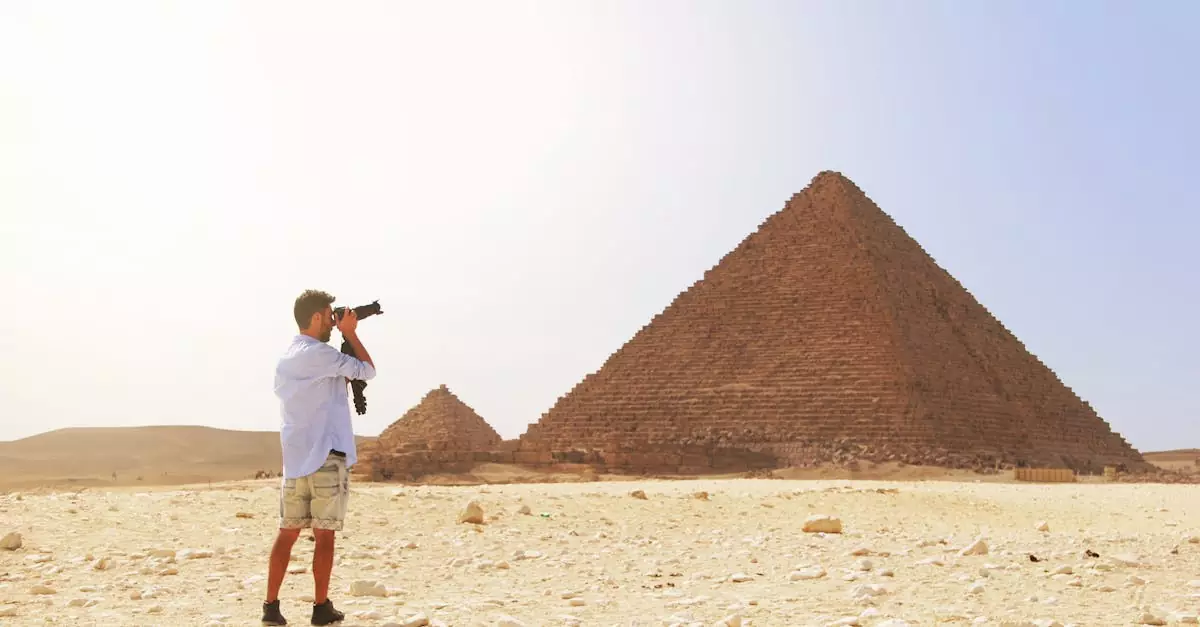 Photographer taking a picture of the Pyramid of Giza under the bright Egyptian sun.
