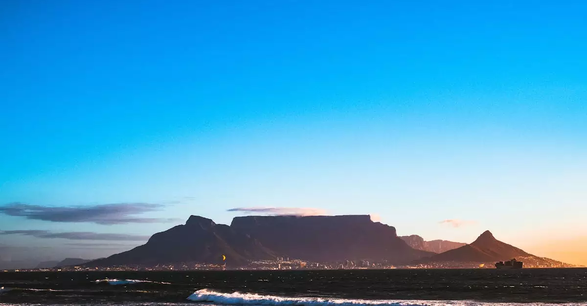 Breathtaking view of Table Mountain with a vivid blue sky and calm ocean waves.