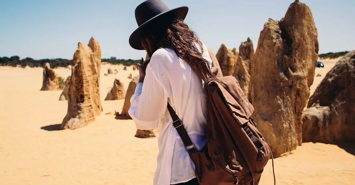 Backpacker with hat exploring rock formations in a sandy desert landscape.