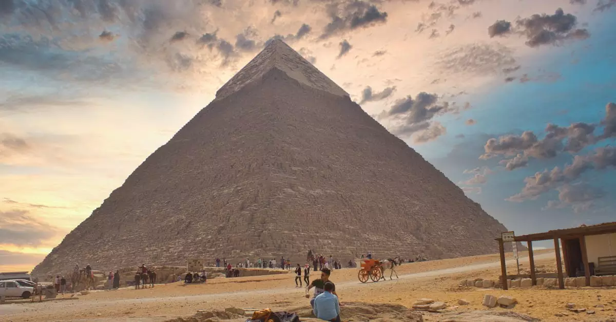 A stunning view of the Great Pyramid of Giza during sunset with a dramatic sky and tourists in Cairo, Egypt.