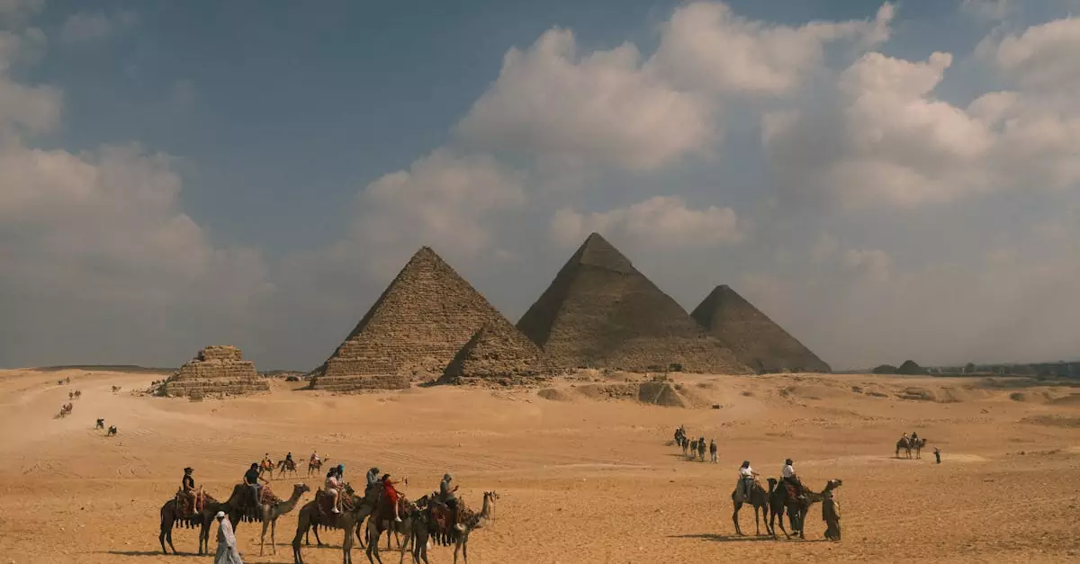 Tourists on camel rides near the iconic Pyramids of Giza under a blue sky.
