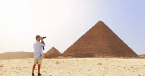 Photographer taking a picture of the Pyramid of Giza under the bright Egyptian sun.