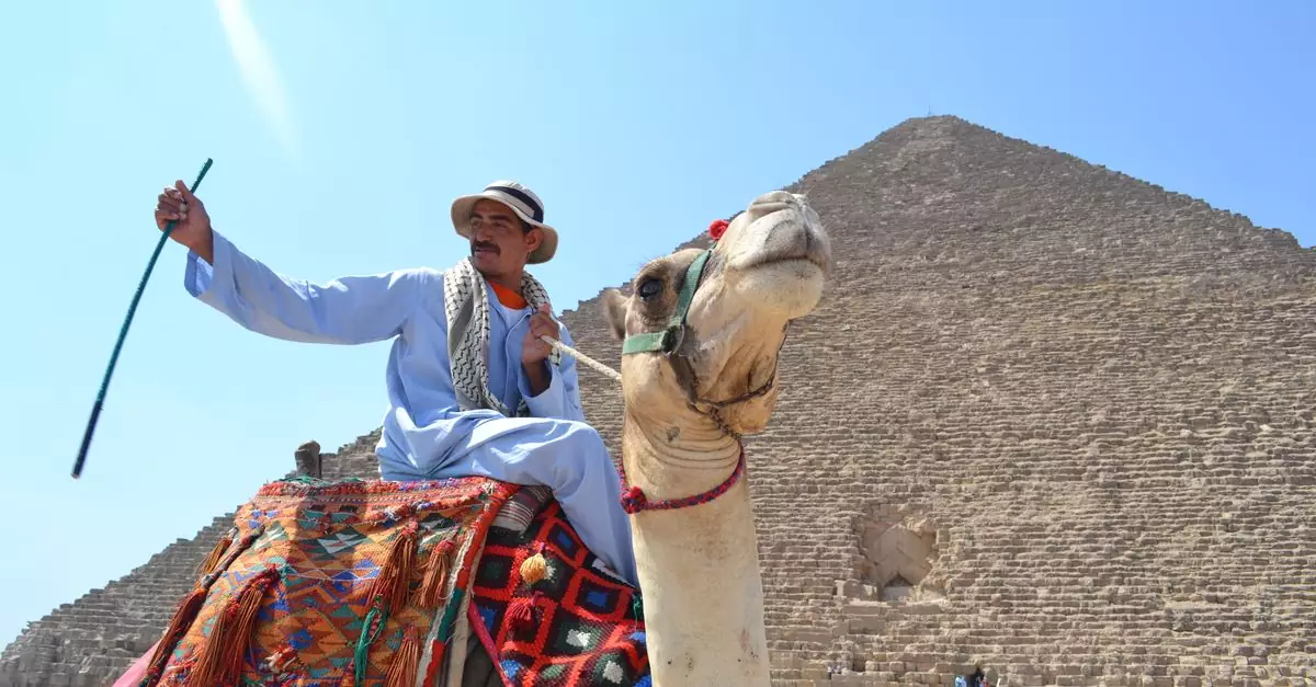 Man riding a camel in front of the Great Pyramid of Giza, a popular tourist attraction in Egypt.