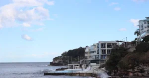 Scenic daytime view of Bondi Beach, showcasing beautiful surf, cliffs, and nearby architecture.