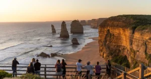 Stunning sunset view of the Twelve Apostles, Victoria, Australia, with tourists enjoying the iconic coastal scenery.