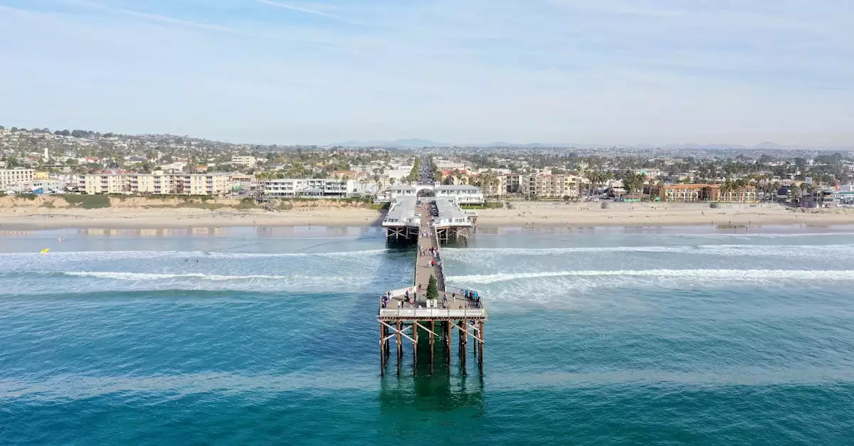 Aerial shot of Crystal Pier in San Diego with clear ocean waves and cityscape in the background.