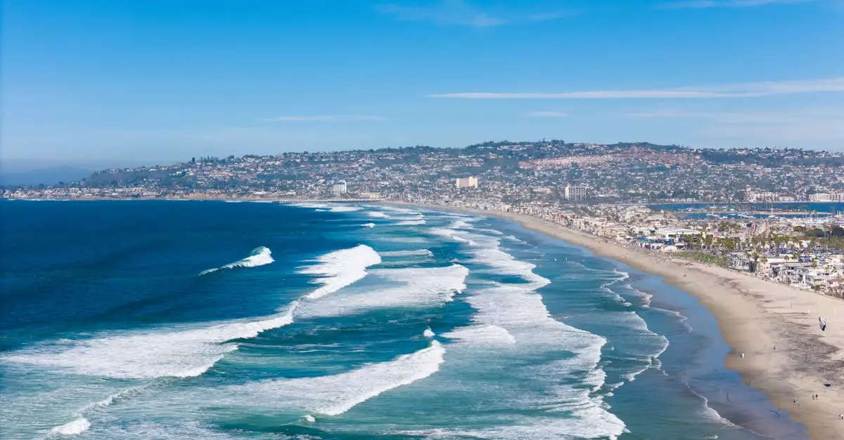 A breathtaking aerial shot of San Diego's coastline, capturing waves and cityscape under a clear sky.