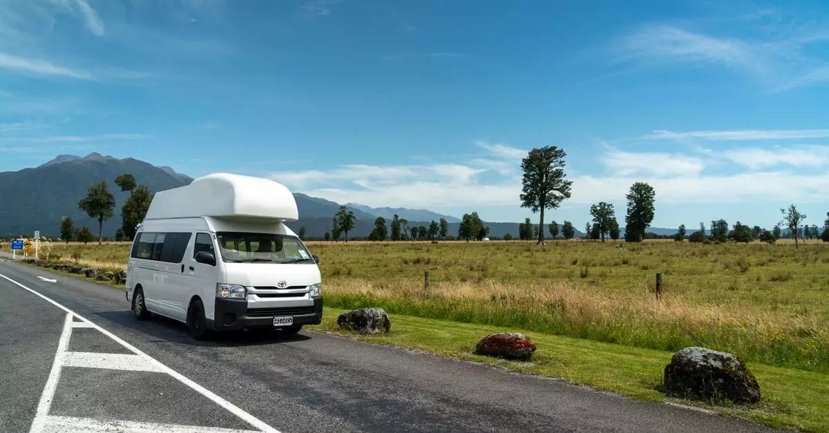 Campervan parked on a picturesque rural road under a clear blue sky.