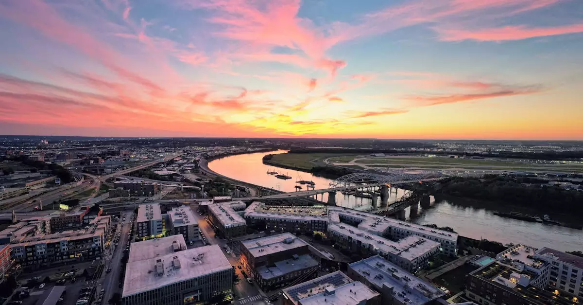 A vibrant sunset over Kansas City's urban landscape and river, highlighting the city's architecture and colorful sky.