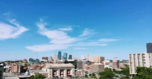Wide-angle shot of Kansas City's skyline with clear blue skies and vibrant green foreground.