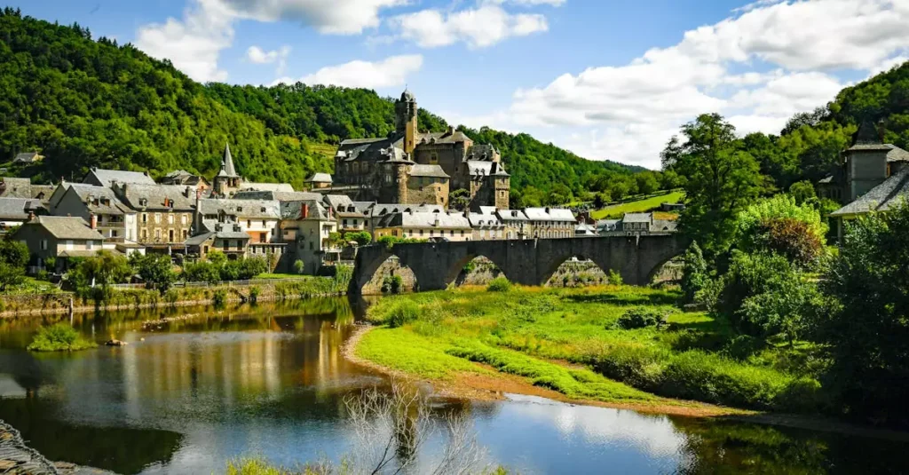 Explore the picturesque village of Estaing and its historic castle surrounded by lush greenery and a serene river.