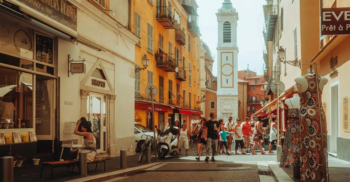 Bustling European street scene with tourists, shops, and a picturesque church tower.