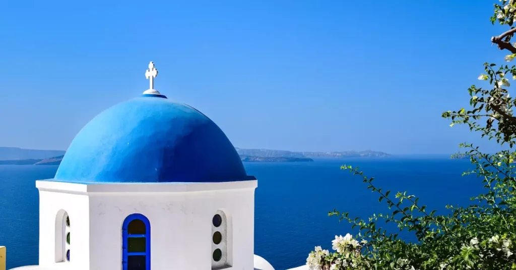 Stunning view of a blue domed church overlooking the Aegean Sea in Santorini, Greece.