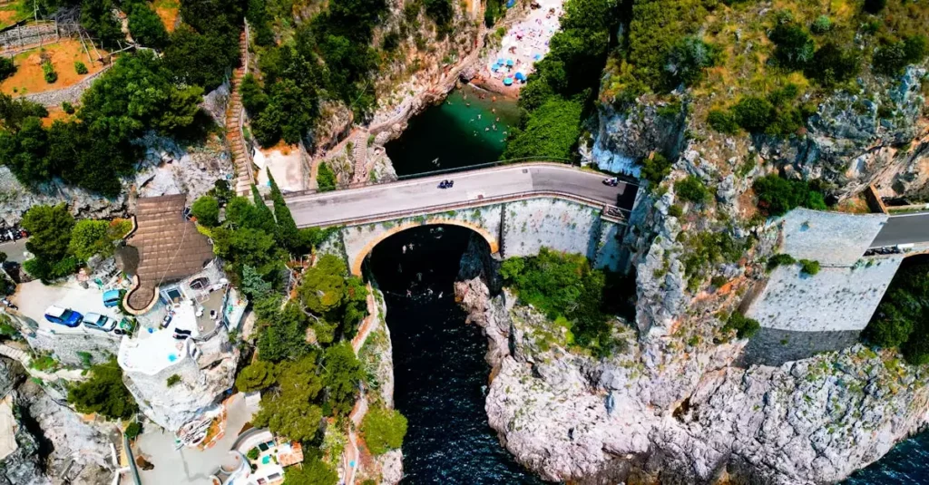 Stunning aerial view of the arch bridge in Furore, Italy, surrounded by cliffs and the Mediterranean.