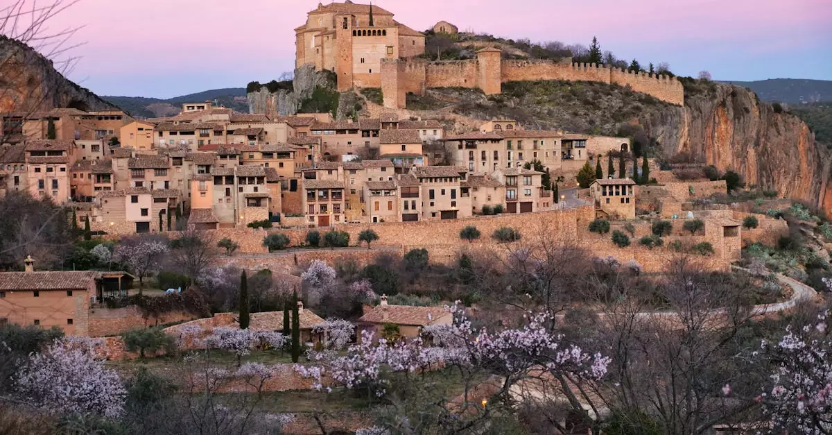 Charming sunset view of Alqu&eacute;zar with its historic hilltop fortification and blooming cherry trees.