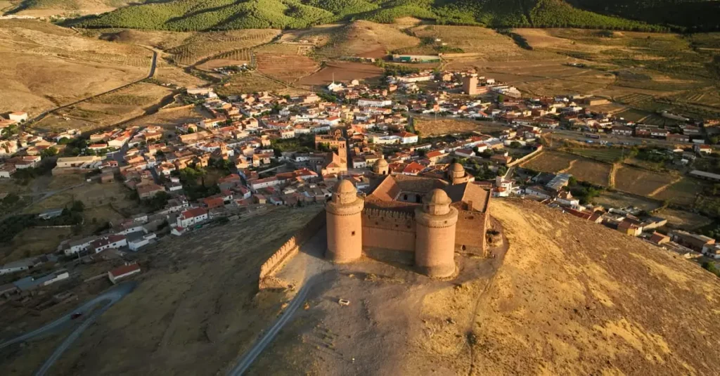 Drone shot of Castillo de La Calahorra overlooking the town and surrounding landscape in Spain.