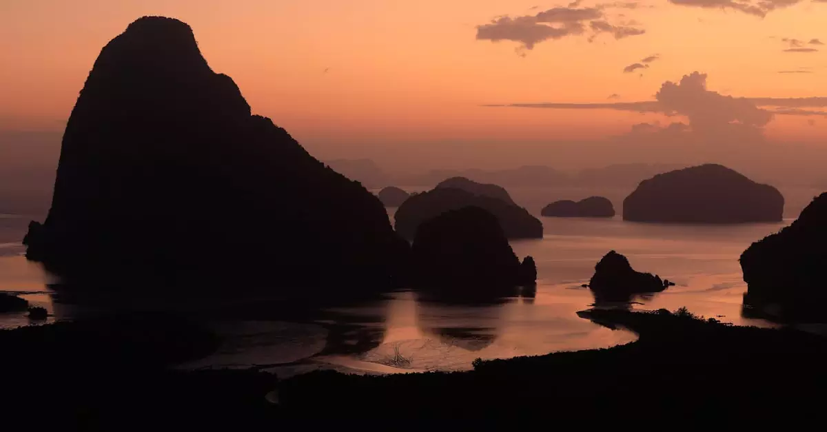 Dramatic silhouettes of rock formations at sunset in Phang-nga Bay, Thailand.