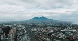 Breathtaking aerial cityscape of Naples overlooking Mount Vesuvius under a cloudy sky.