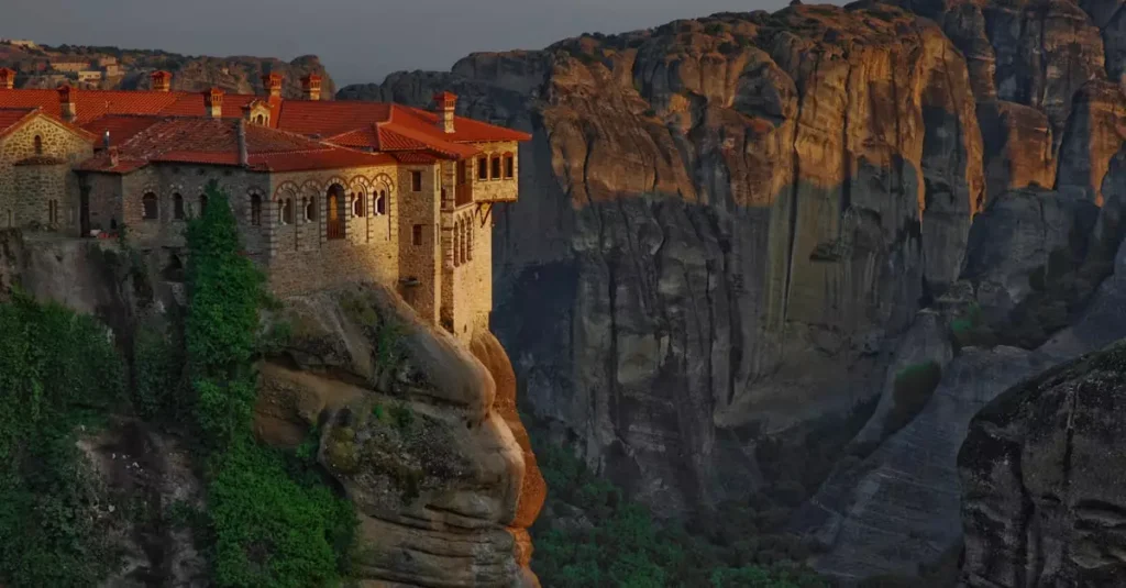 Best Monasteries in Greece: A Spiritual Guide 2 Breathtaking sunset view of Great Meteoron Monastery perched on a cliff in Meteora, Greece.