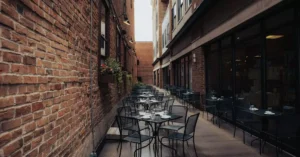 A quaint alley café with empty tables set against brick walls, creating a cozy urban ambiance.