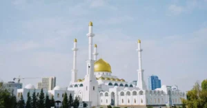The stunning Nur-Astana Mosque in Kazakhstan with its iconic golden domes and minarets against a bright blue sky.