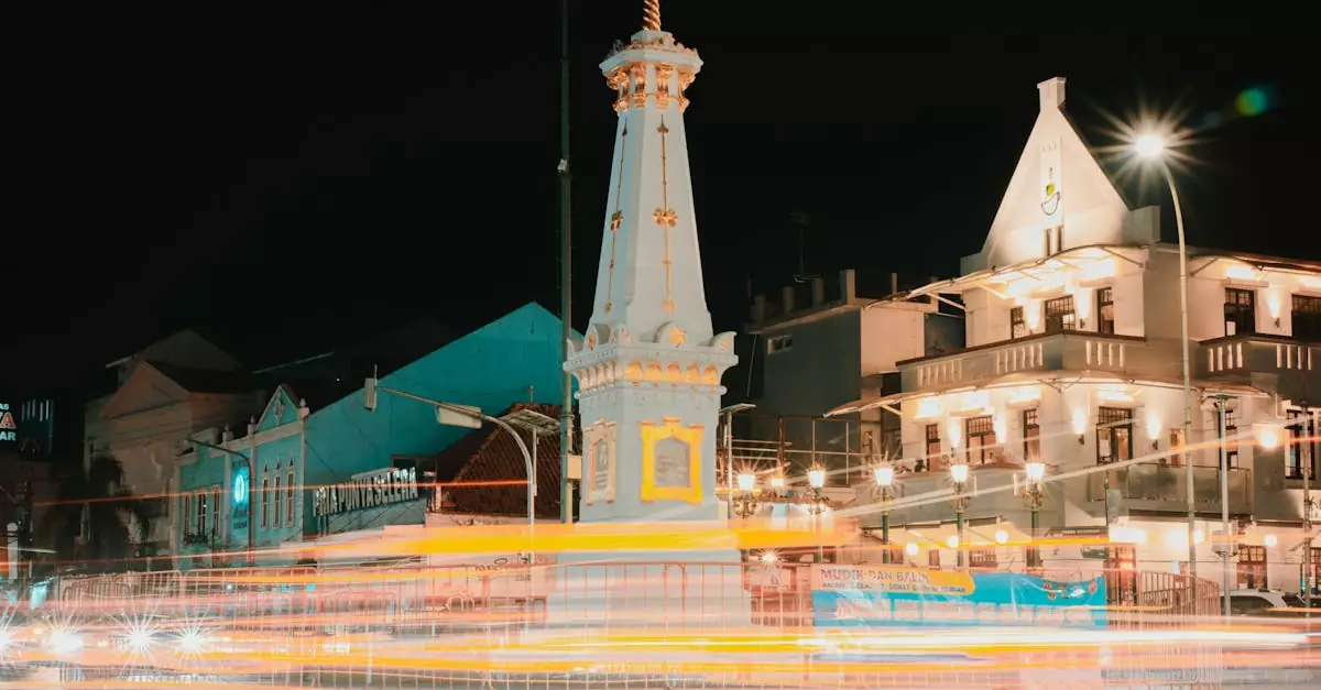 Captivating long exposure of Tugu Yogyakarta with vibrant traffic light trails at night showcasing urban life.