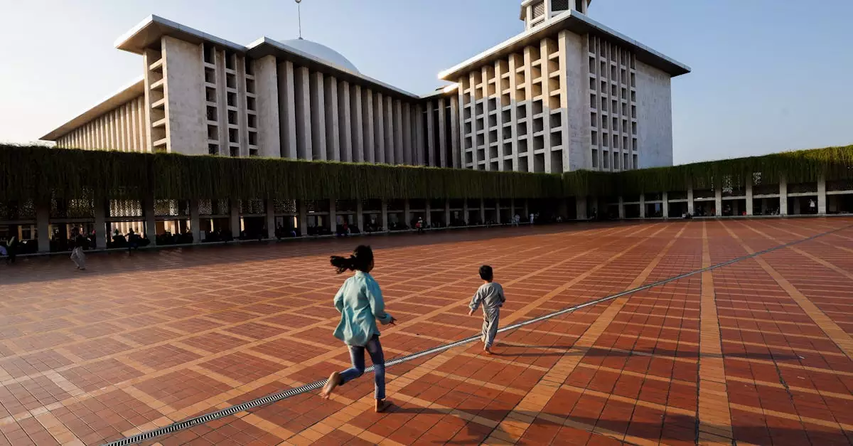 Two children running playfully at Istiqlal Mosque courtyard, Jakarta, during daylight.