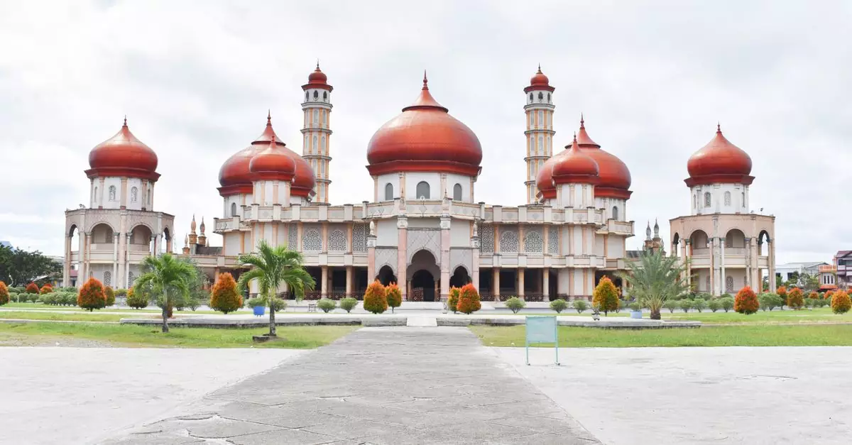 Beautiful mosque with striking red domes and minarets, featuring intricate architecture against a cloudy sky.