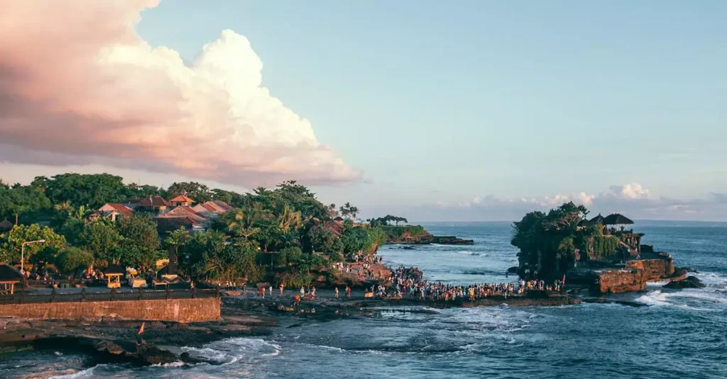 Best Places to Visit in Indonesia: Top Destinations 12 Travelers on stone shore with green tropical plants washed by foamy waves of sea