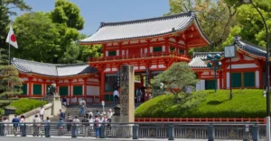 Vibrant scene of Yasaka Shrine entrance in Kyoto, Japan during a sunny day, filled with visitors.