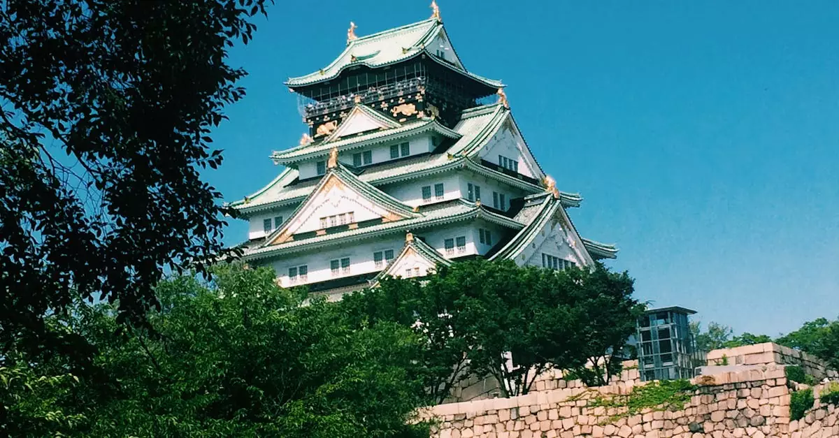 Osaka Castle surrounded by lush greenery under a clear blue sky, captured on a sunny day.
