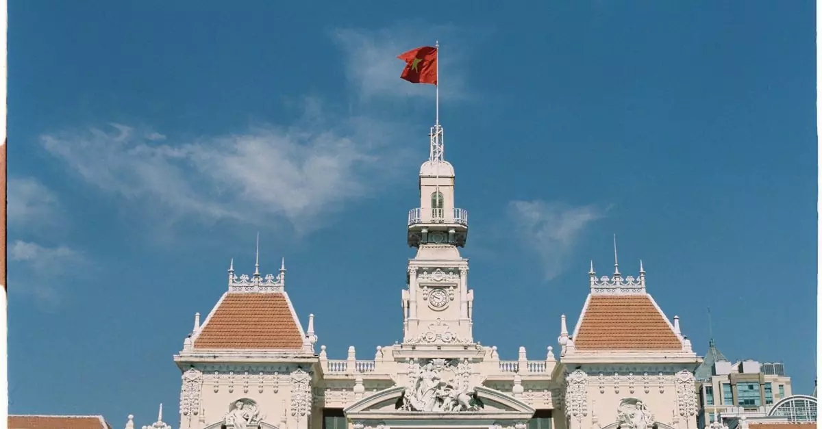 Iconic Ho Chi Minh City landmark with Vietnamese flag against a clear blue sky.