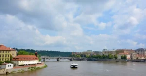 A serene day on the Vltava River in Prague surrounded by historic architecture and lush greenery.