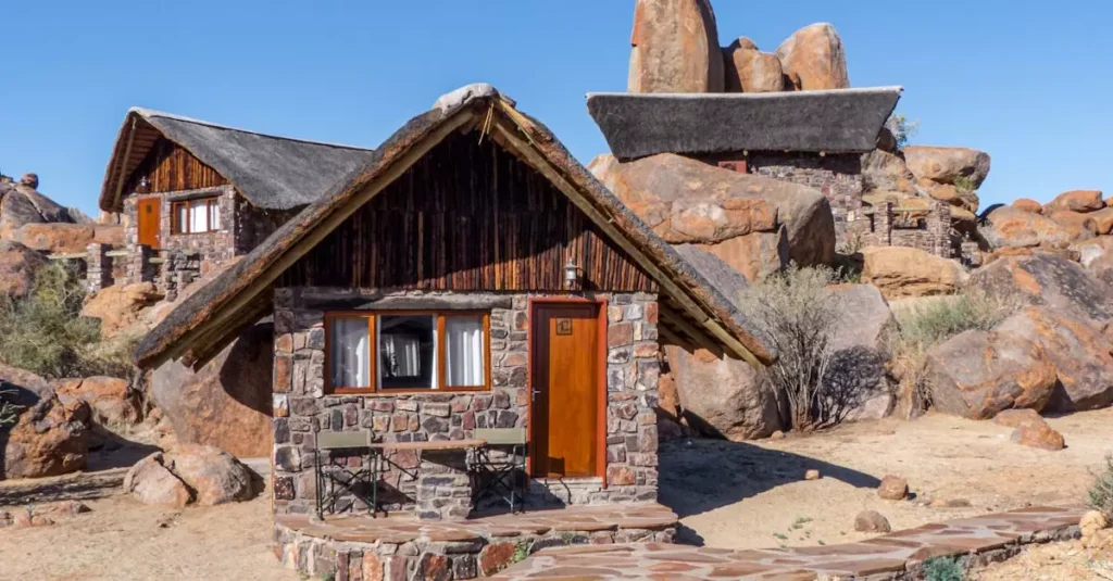 Cozy stone cabin nestled among natural rock formations in Namibia's desert setting.