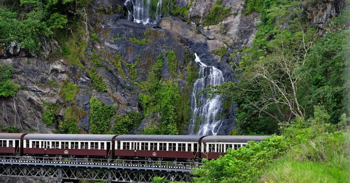 A vintage train crossing a bridge by Barron Falls in lush Queensland rainforest scenery.