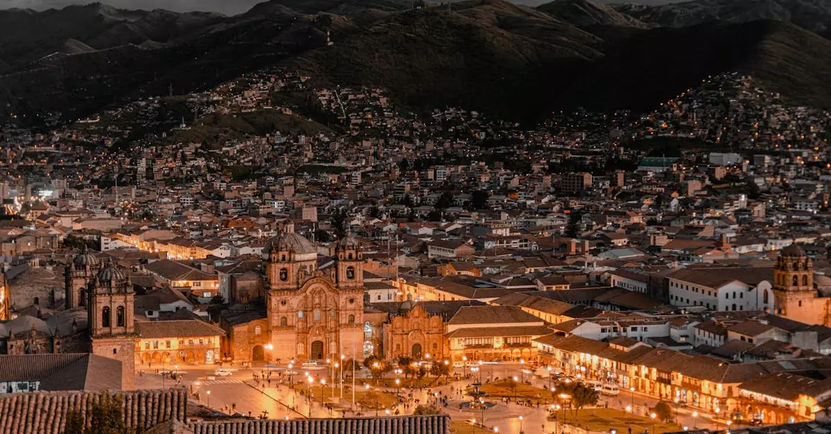 Aerial view of Cusco, Peru at twilight showcasing illuminated buildings and historic architecture.
