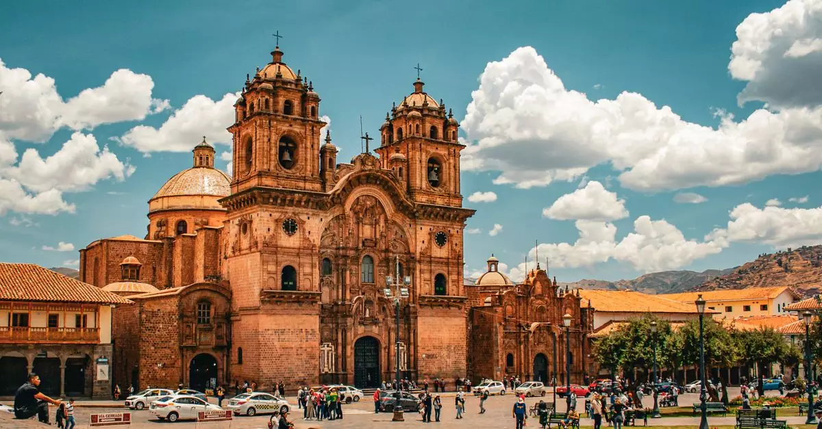 View of a historic church in Cuzco, Peru with a bustling city street.