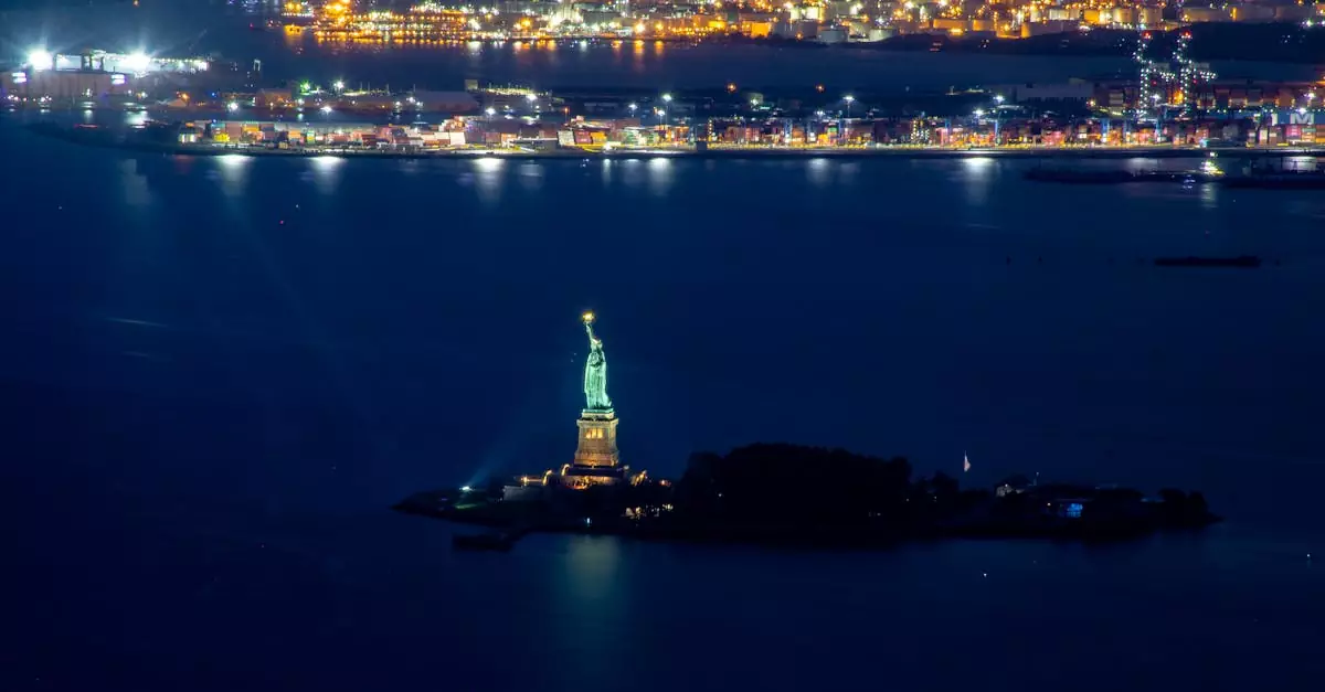 A stunning aerial view of the Statue of Liberty illuminated at night with city lights in the background.