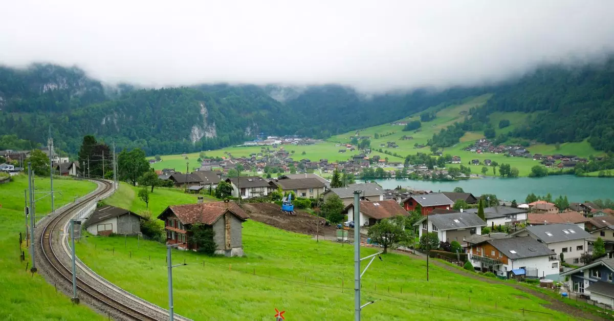 Beautiful shot of Lungern village in Switzerland with lush green hills and railway. Misty mountains in the backdrop.