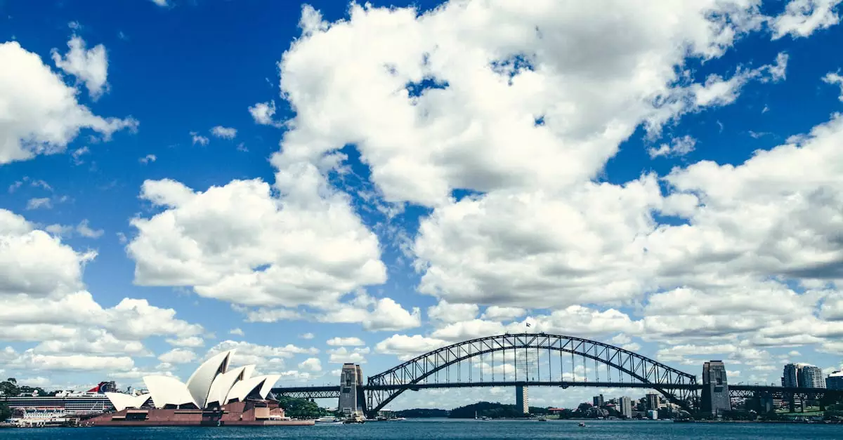 A stunning view of the Sydney Harbour Bridge and Opera House with a bright blue sky and white clouds.
