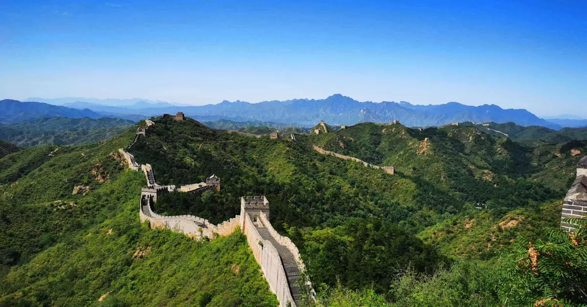 Stunning aerial view of the Great Wall of China winding over lush green hills under a clear blue sky.