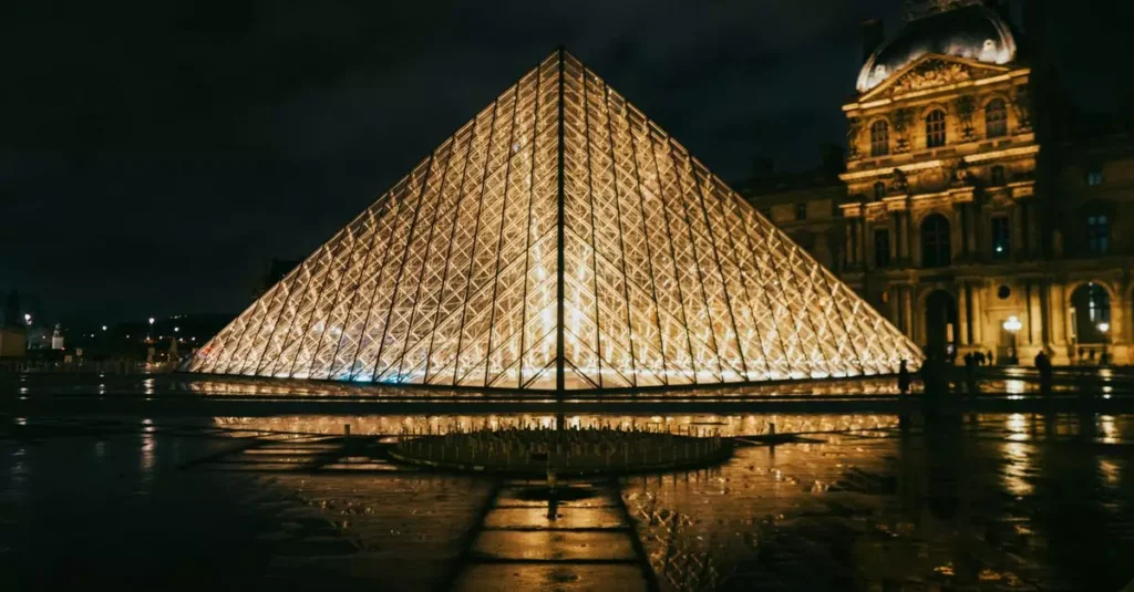 View of the Louvre Pyramid glowing at night, showcasing modern architecture in Paris, France.