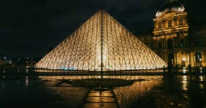 View of the Louvre Pyramid glowing at night, showcasing modern architecture in Paris, France.