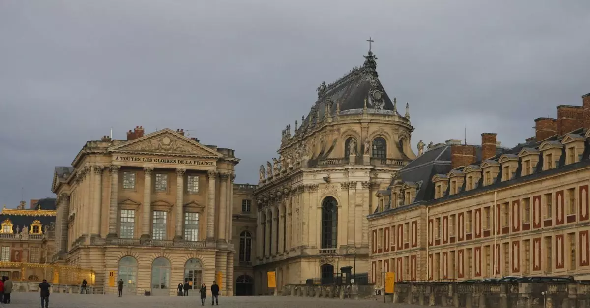 Historic Versailles Palace showcasing classic French architecture under a cloudy sky.