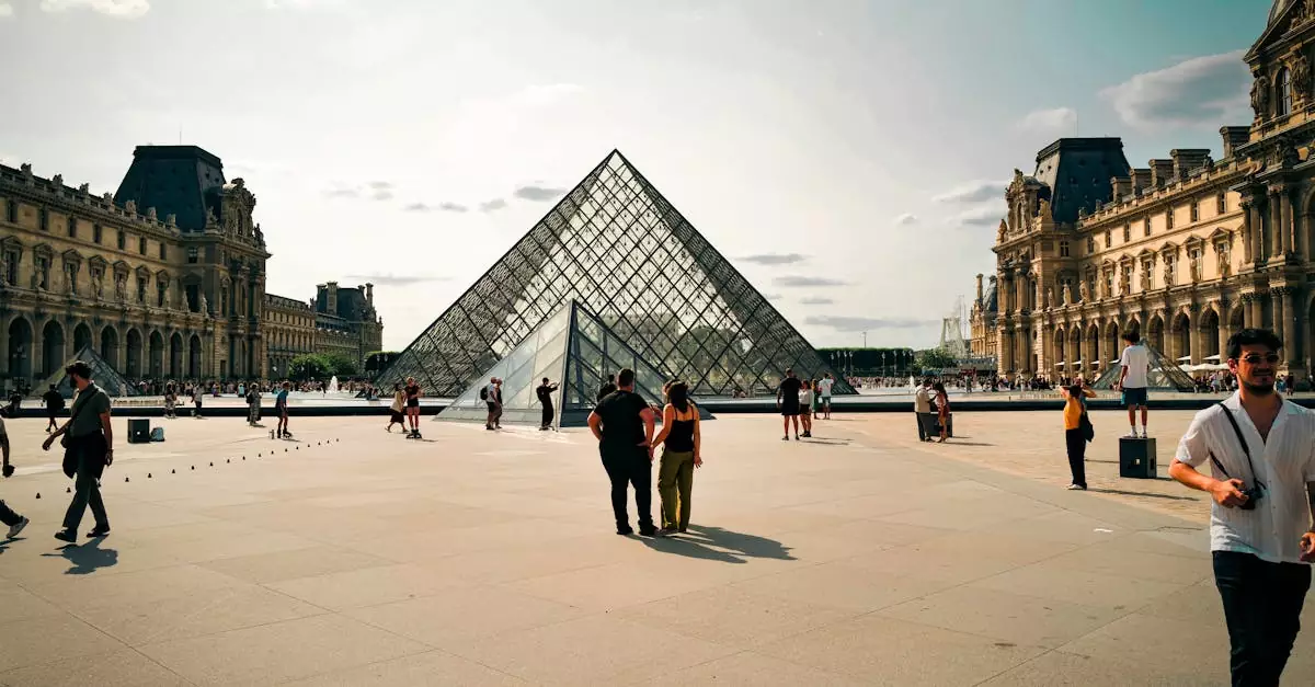 A daytime view of the Louvre Pyramid in Paris with people walking around.