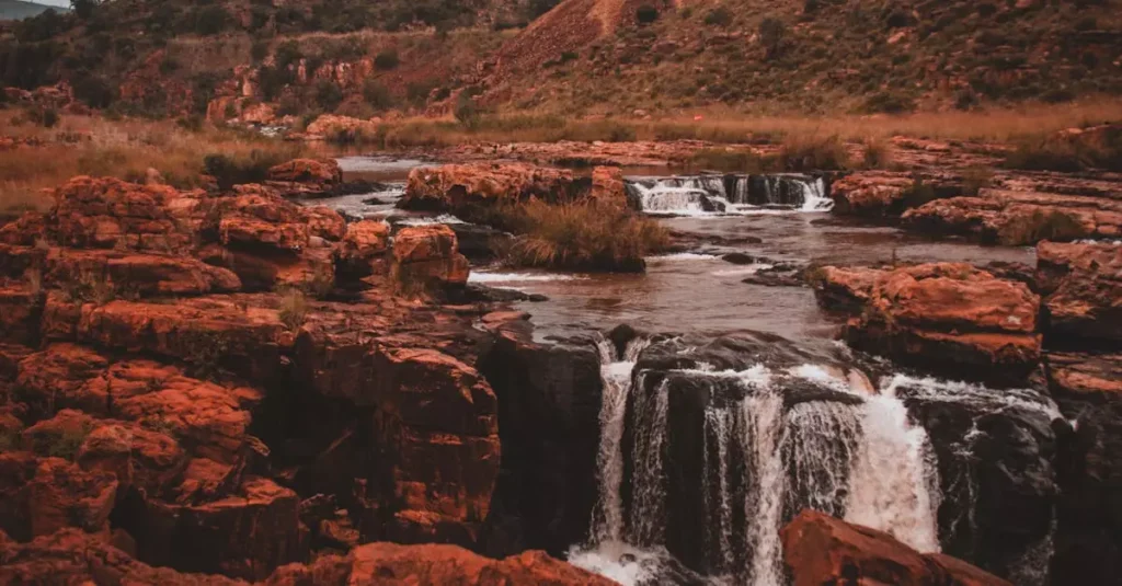 Captivating scene of cascading waterfalls in a red rock canyon during sunset.