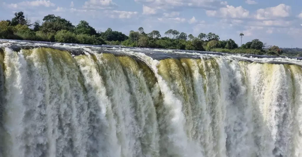 Stunning view of Victoria Falls cascading with vibrant energy, surrounded by lush greenery.