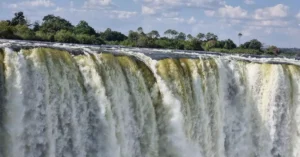 Stunning view of Victoria Falls cascading with vibrant energy, surrounded by lush greenery.